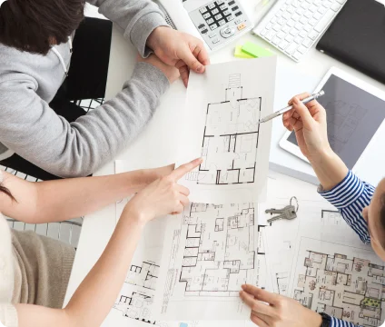 テーブルに広げた間取り図と資料を見ながら中古マンションの条件を相談する手元